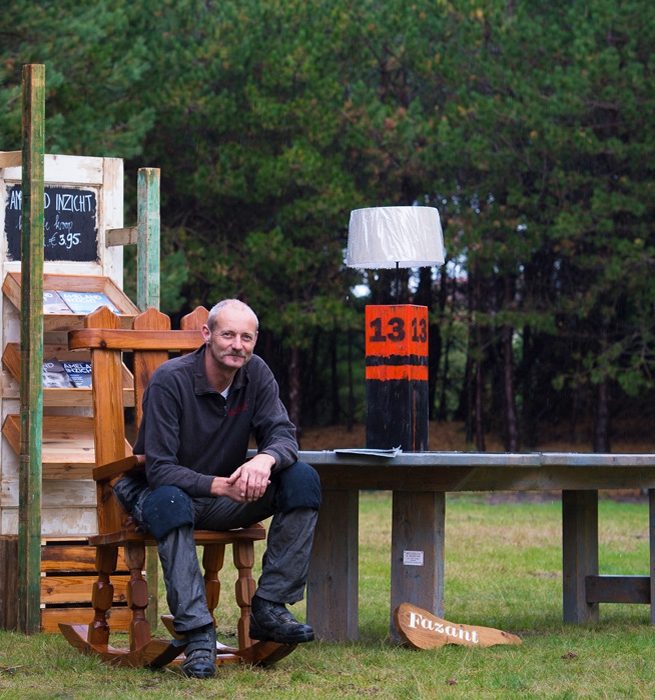 Benno Hesselink tussen zelfgemaakte houten meubels in de bossen van Ameland